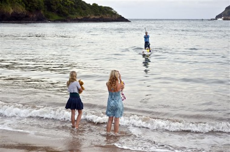 Bart de Zwart paddles the final few yards of his 300-mile paddleboard trip from the Big Island to Kauai on Sunday. He is greated by his daughter, Soleil, left, and wife, Dagmar de Zwart. 